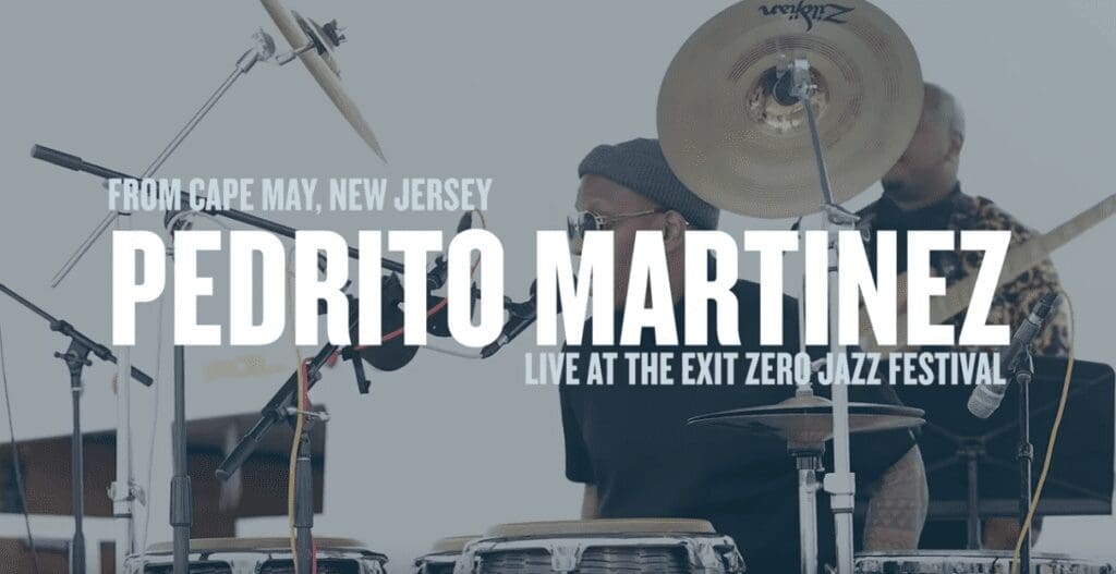 A man playing drums in front of other people.