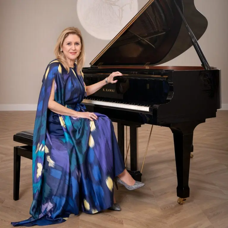 Image of Founder Victoria Montserrat seated at an ebony colored grand piano.